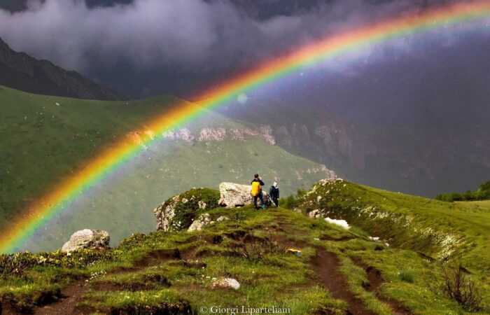 Touristen mit Regenbogen in Stapantsminda auf Rundreise Georgien für Selbstfahrer